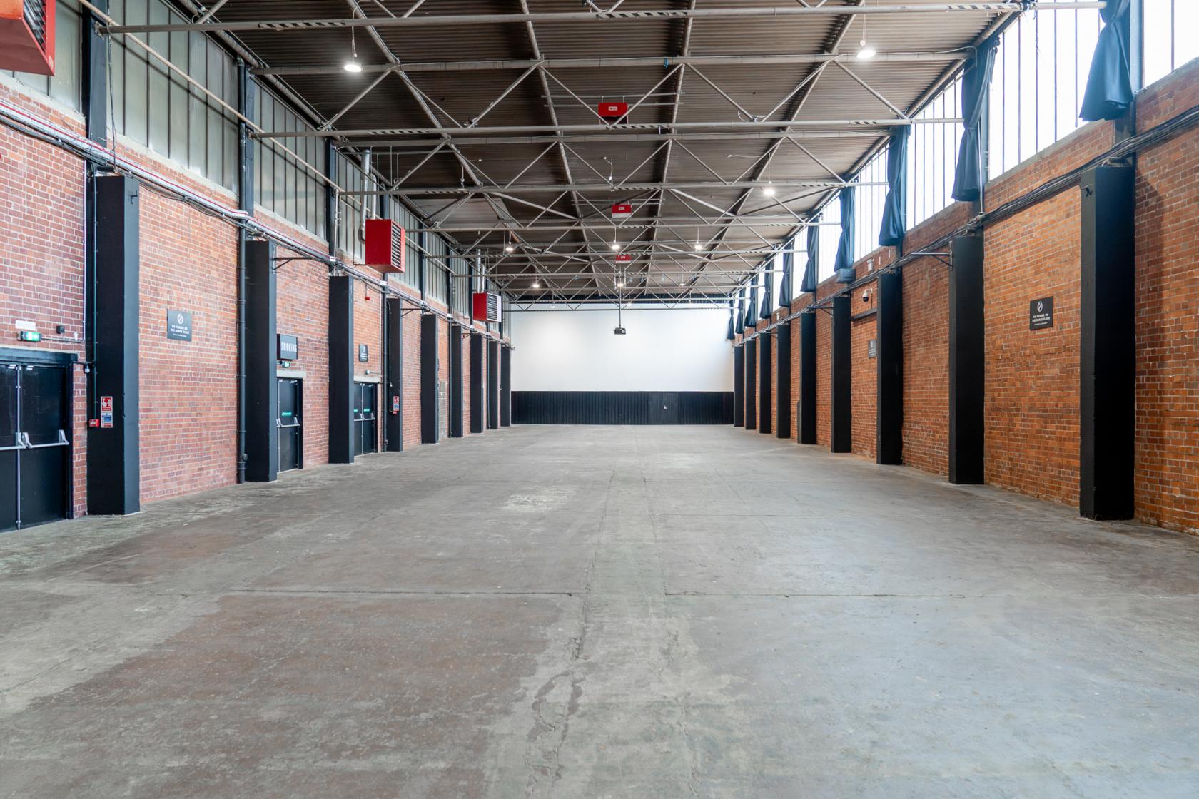 A spacious warehouse with exposed brick walls, high ceilings, and industrial lighting at TESTBED.