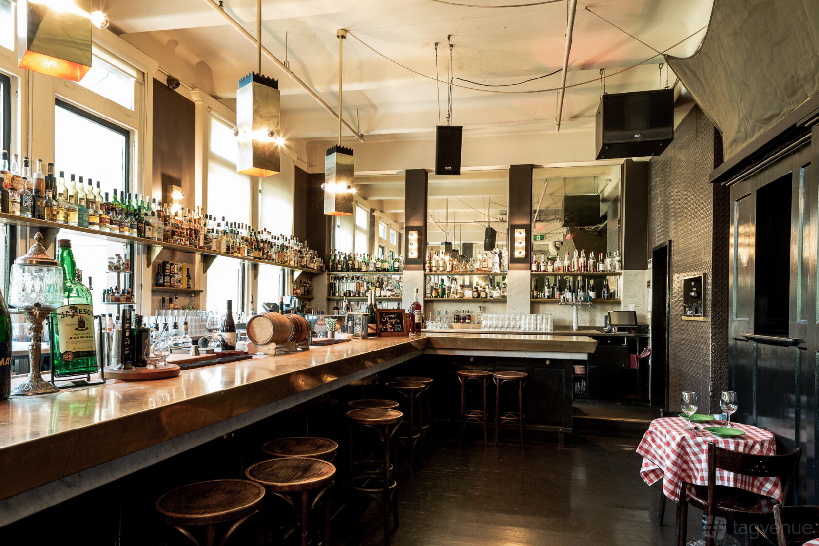 A nightclub with a long wooden bar, mirrored walls, and high windows at The Toff.