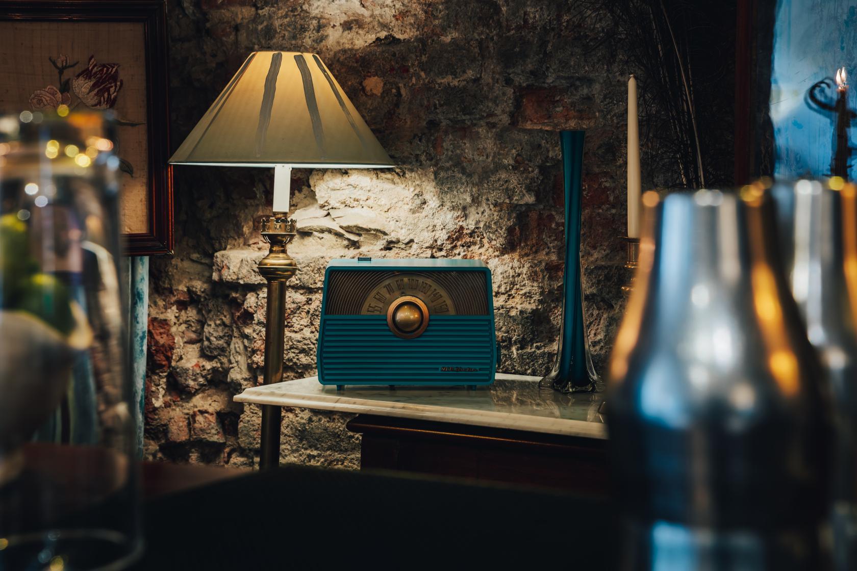 A meeting room with a vintage lamp, exposed brick wall, blue retro radio, and candle at The Zetter Clerkenwell.