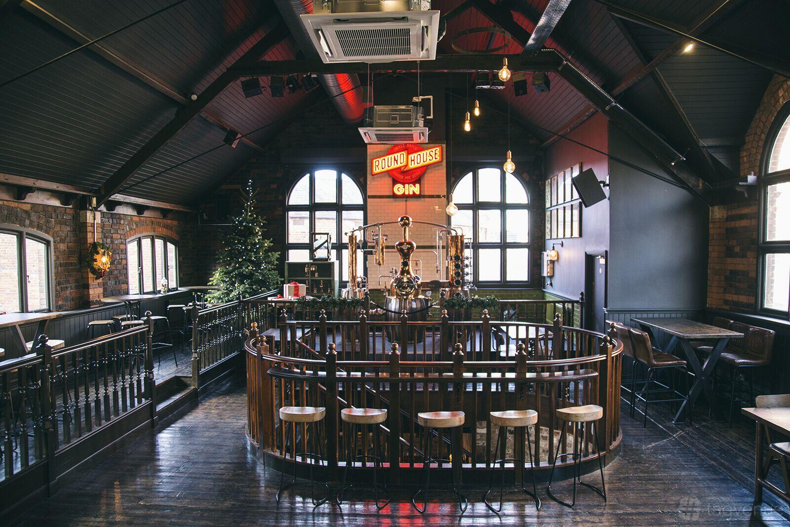 An event space in a bar with large arched windows, high ceilings, and a gin still at The Distillery.