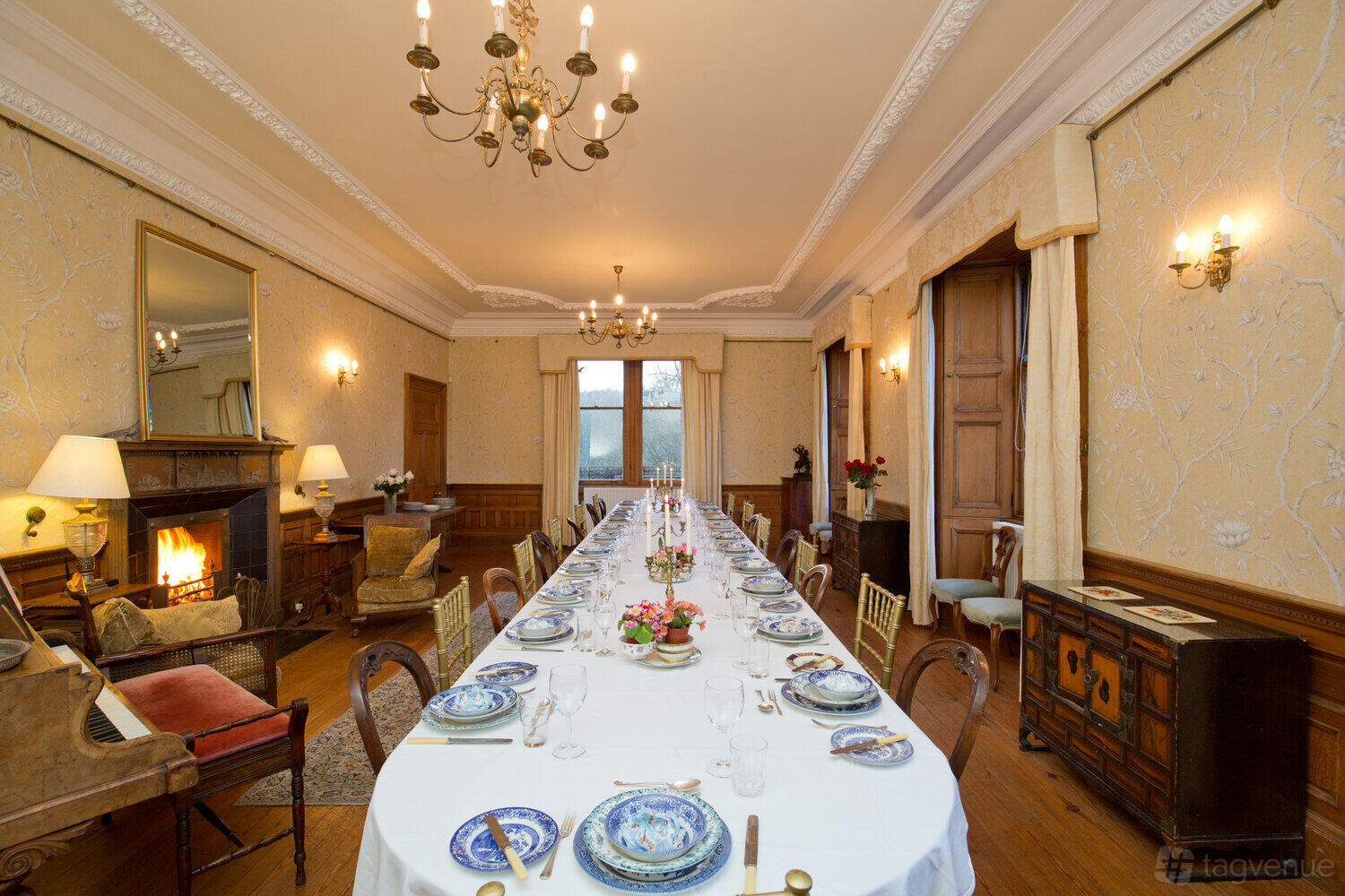 A country house dining room with a long banquet table, fireplace, ornate ceiling, and chandeliers at Kippilaw House.