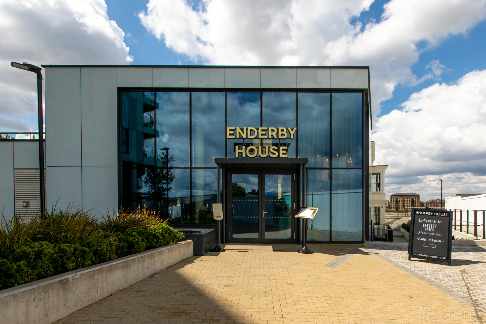 A versatile event space with a glass-front entrance, gold signage, and landscaped walkway at Enderby House.