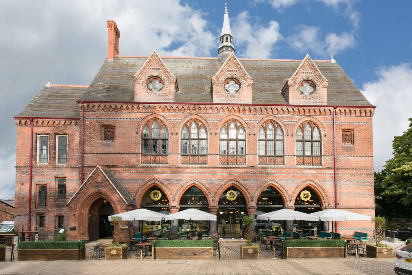 A versatile event space with a red brick Gothic Revival façade and outdoor seating at The Lost and Found Knutsford.