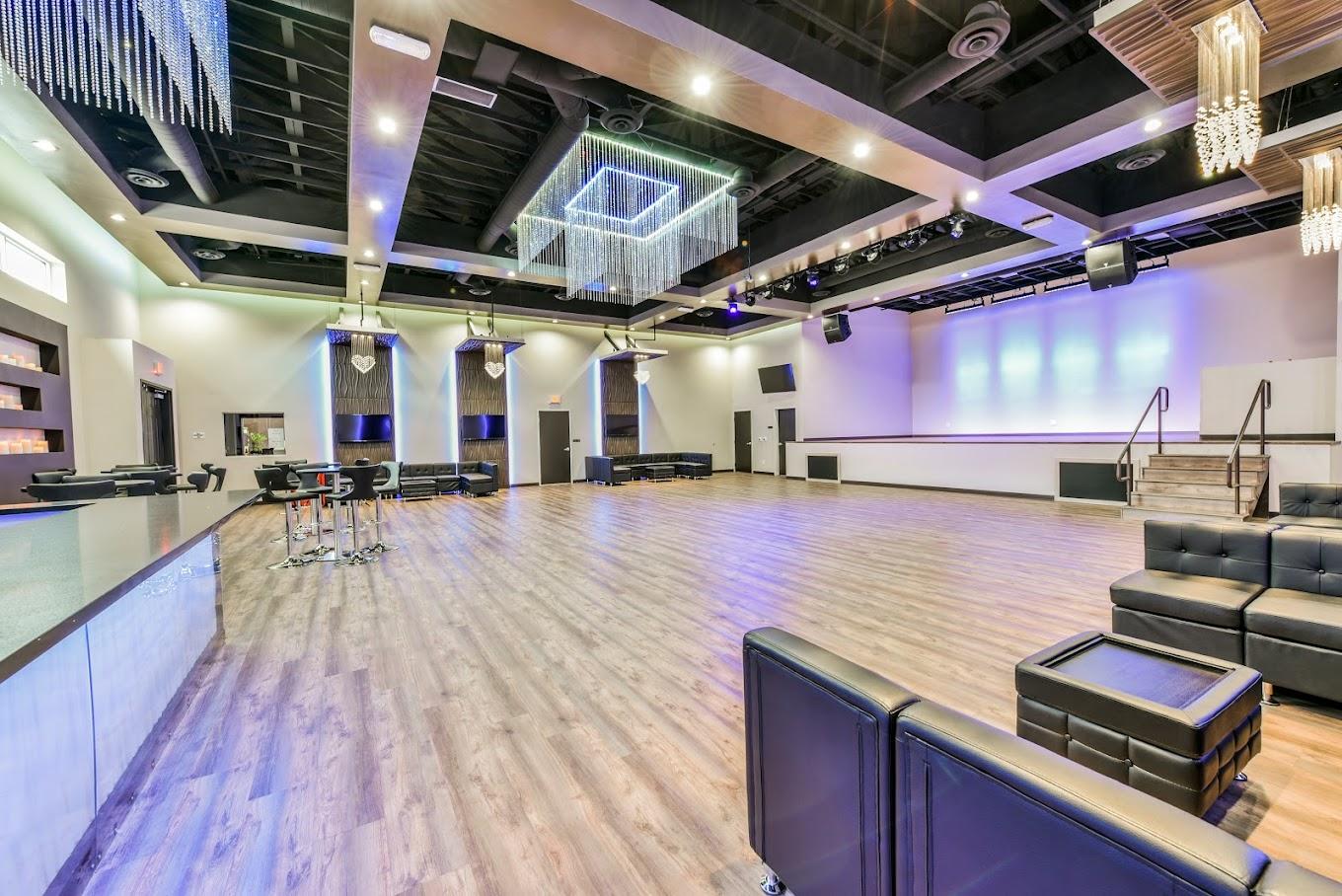A dance studio with wood floors, lounge seating, and modern chandeliers at Rhythms Dance Studio & Event Center.