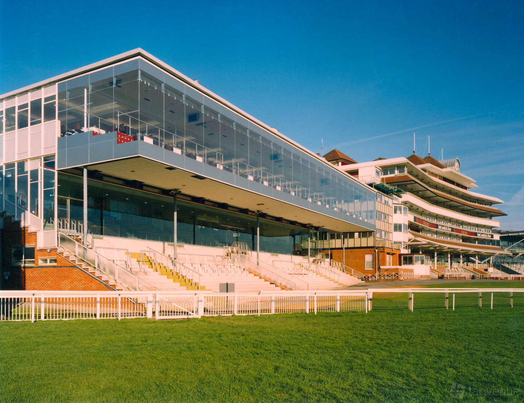 A versatile event space with tiered seating, glass-fronted upper levels, and open views at Newbury Racecourse.