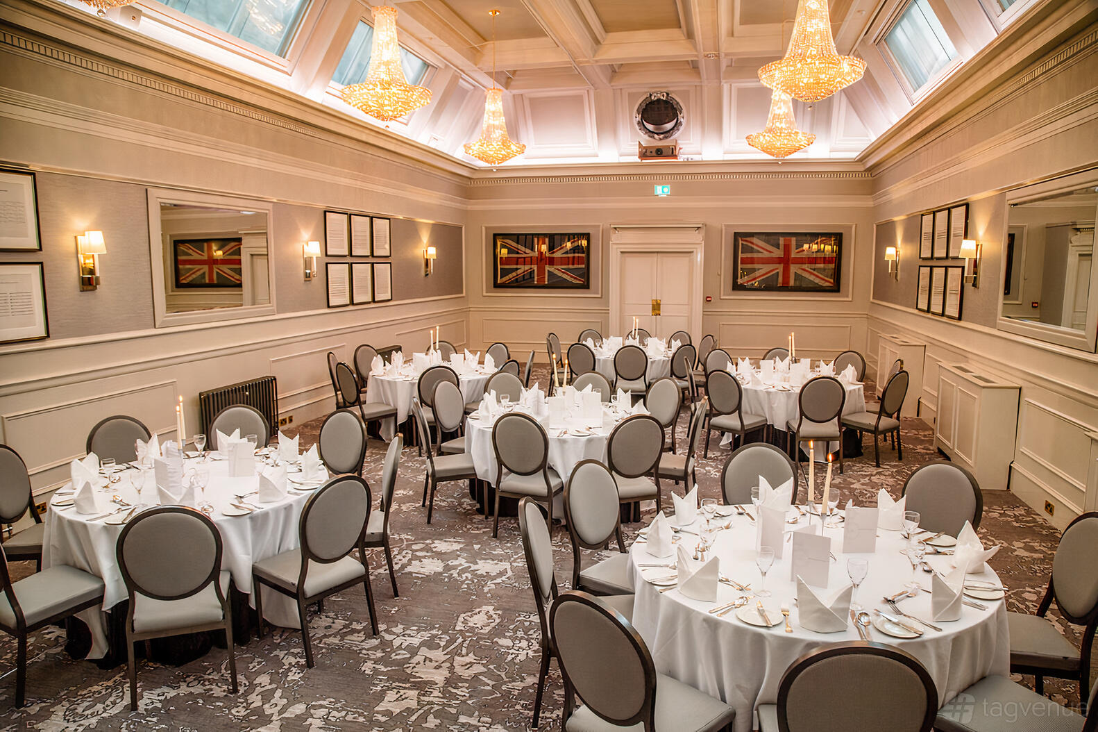 A banqueting hall with skylights, chandeliers, and round tables with white linens at Royal Scots Club.