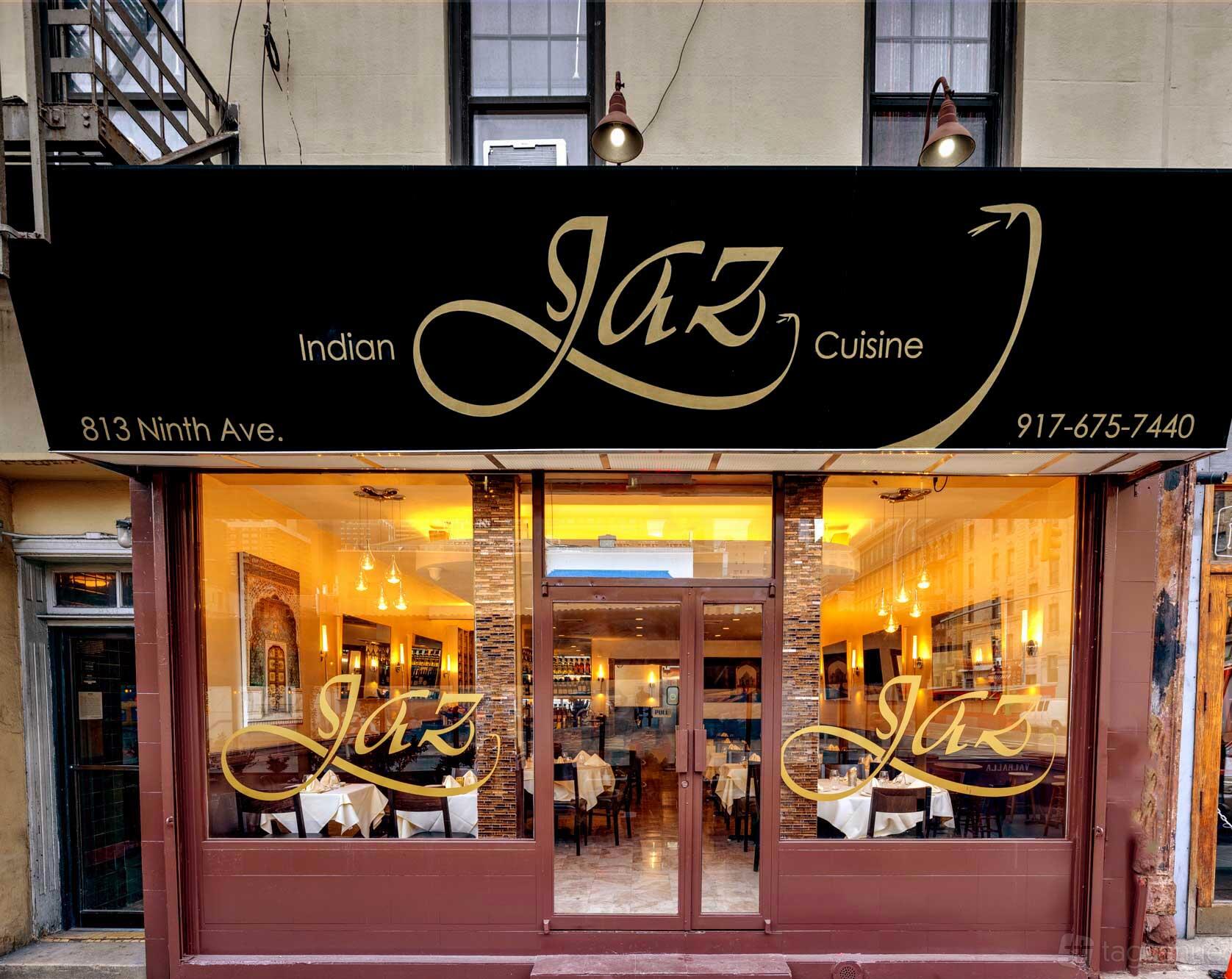 A restaurant with large glass windows, black and gold signage, and warmly lit dining tables at Jaz Indian Cuisine.