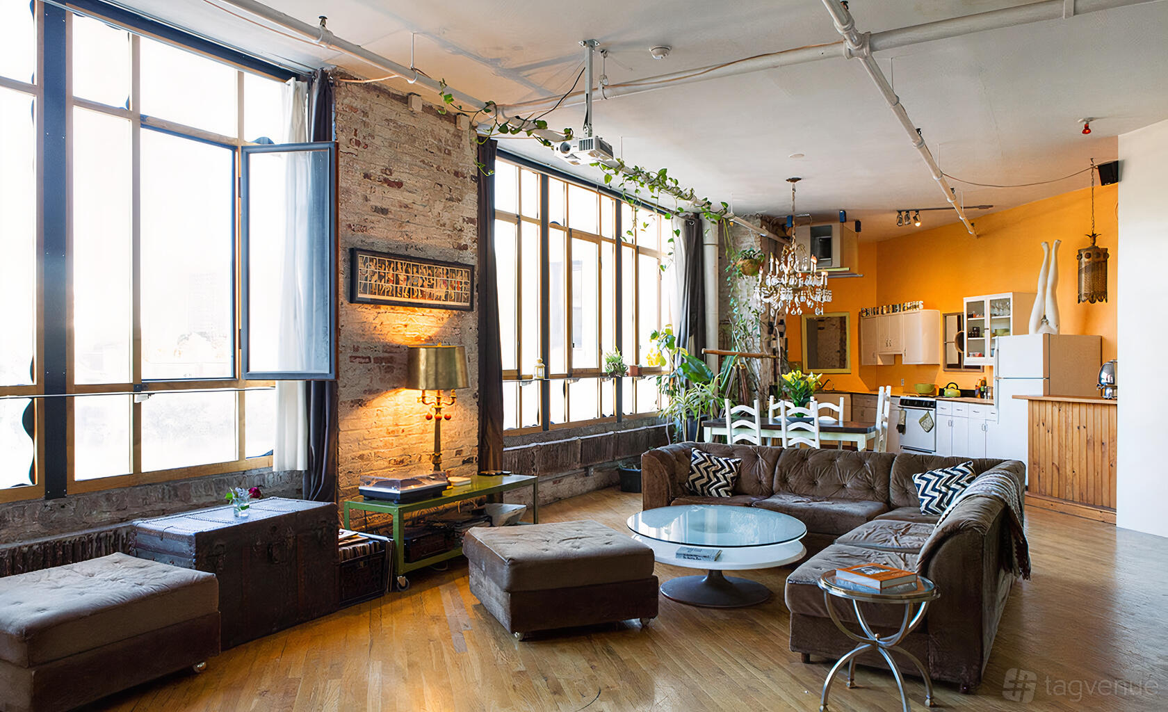 An apartment with exposed brick walls, large industrial windows, and an open kitchen at 100 White Street Studios.