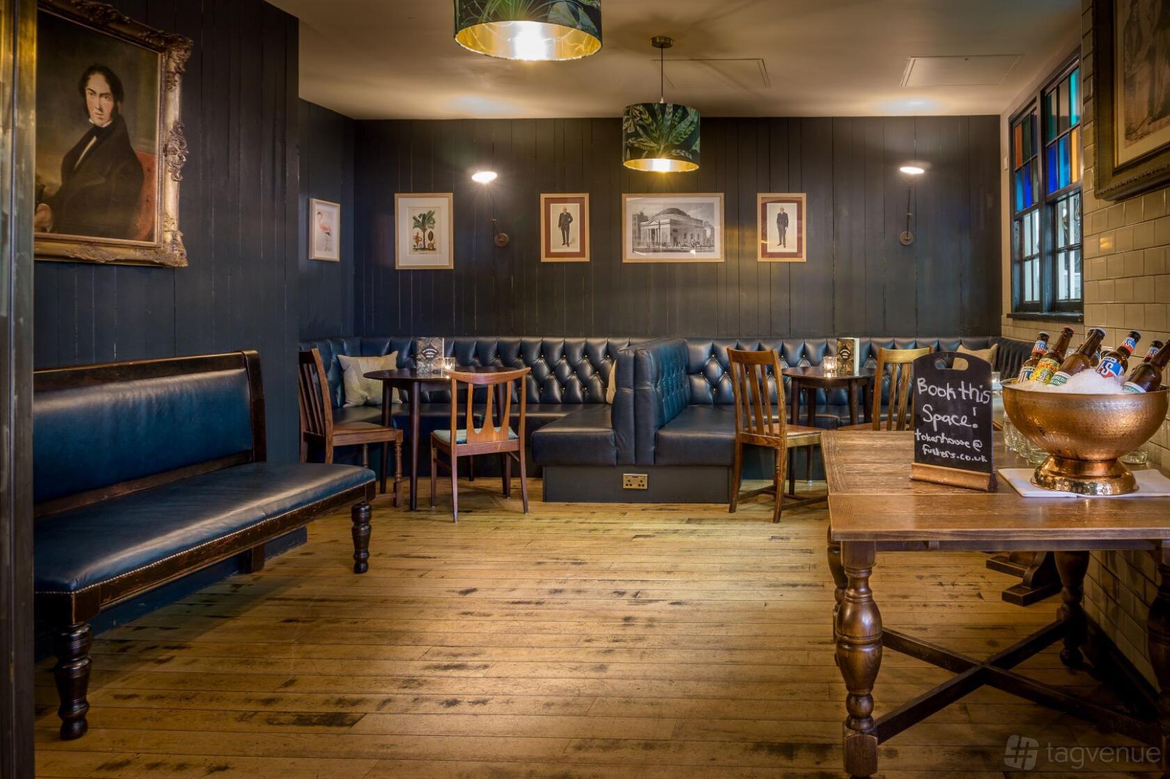 An event space in a pub with dark paneled walls, framed artwork, and leather banquette seating at Tokenhouse.
