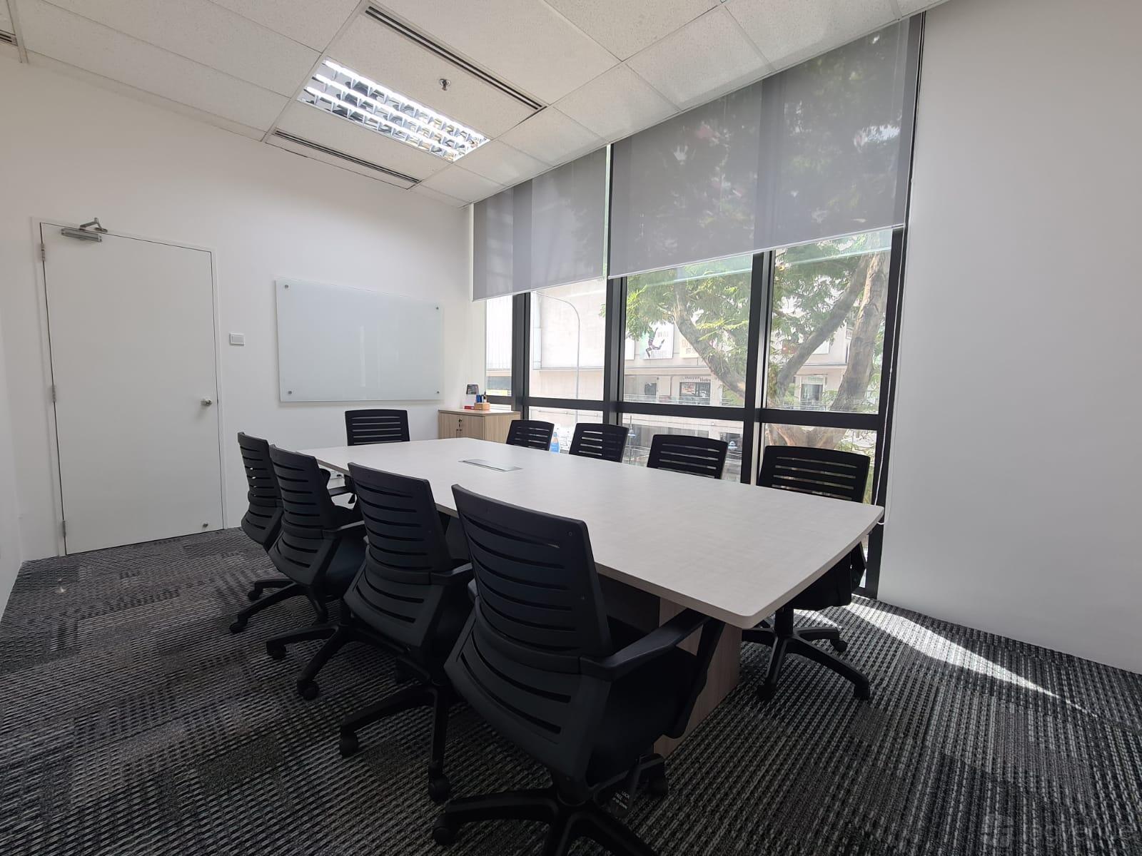 A meeting room with a long conference table, black chairs, a whiteboard, and large windows at Starich Meeting Rooms.