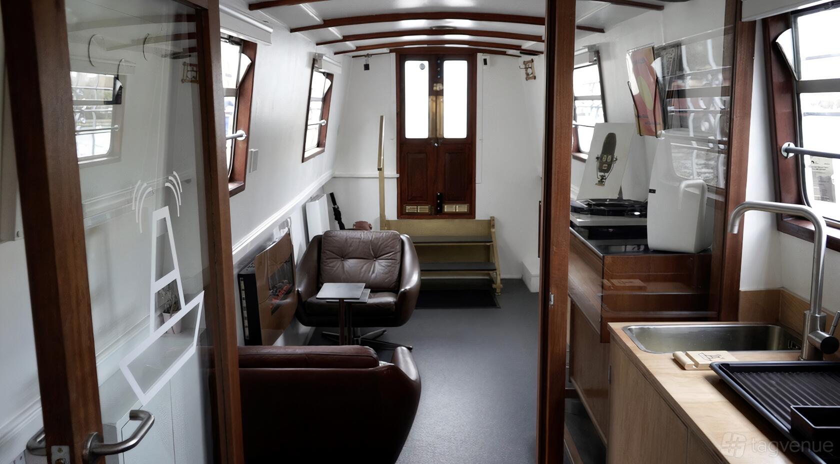 A boat venue with leather armchairs, wood panel accents, and large windows at The BoAt Pod.
