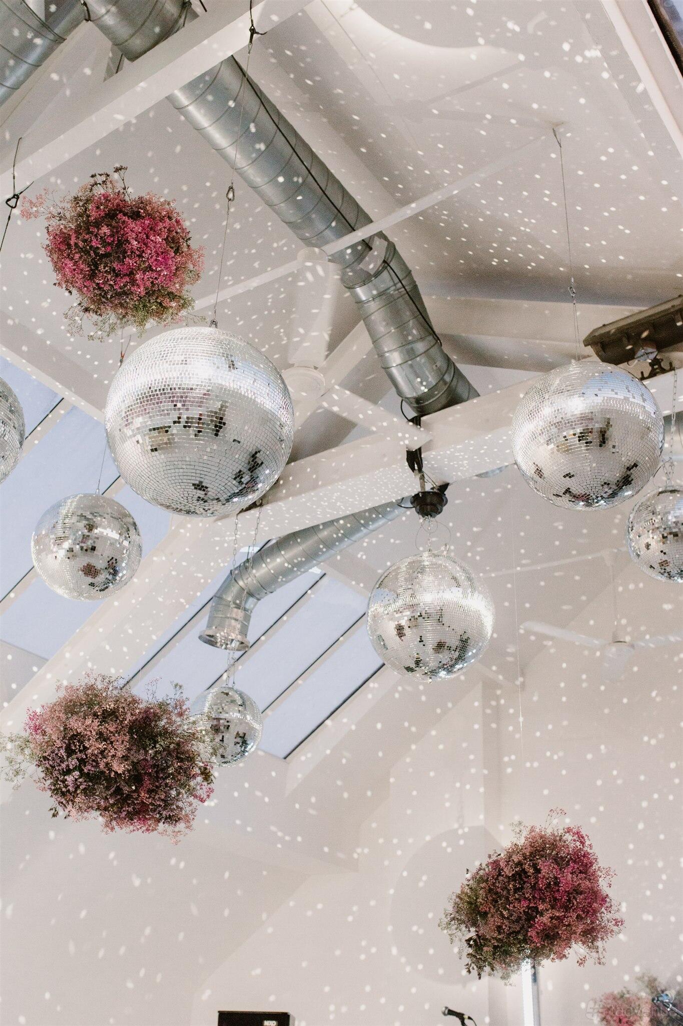 An event venue with large mirrored disco balls and exposed ductwork on a white beam ceiling at fivefourstudios.