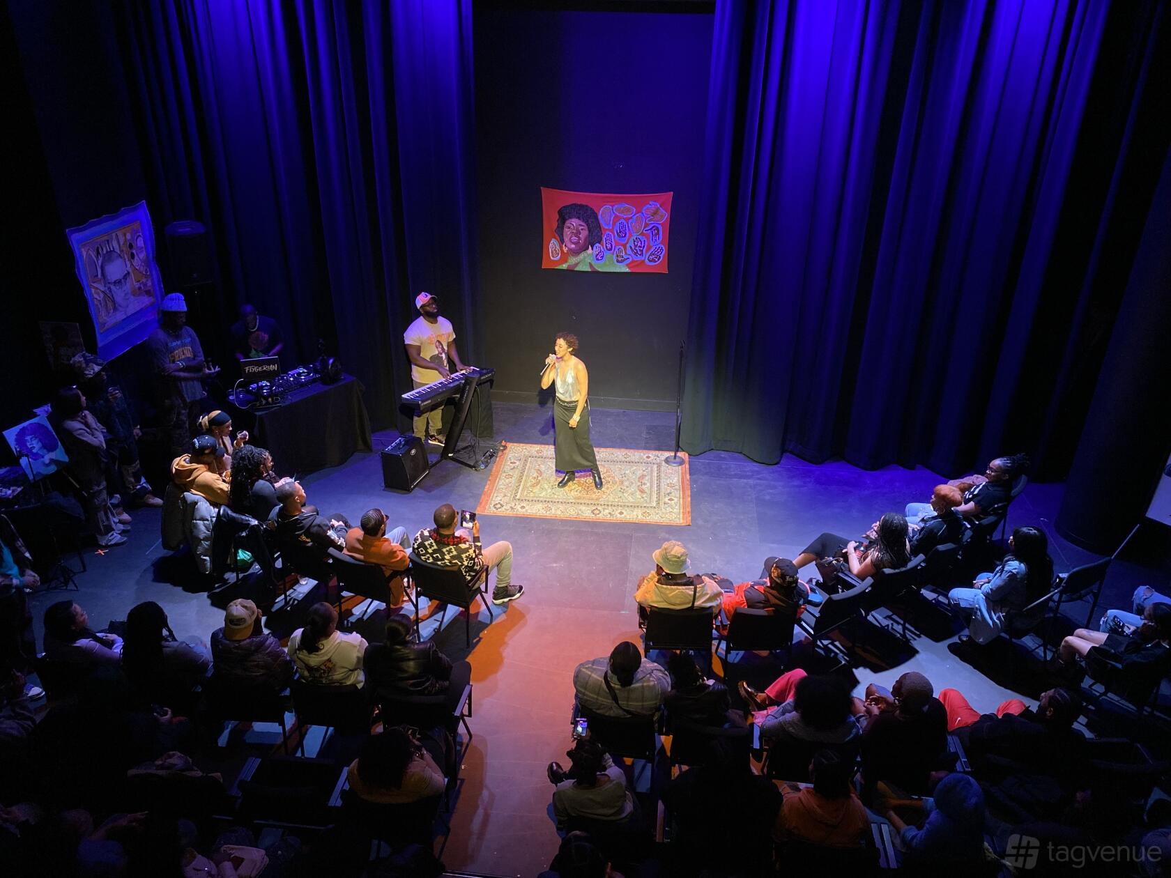 A black box theater with a raised stage, theatrical lighting, and audience seating at Art House Productions.