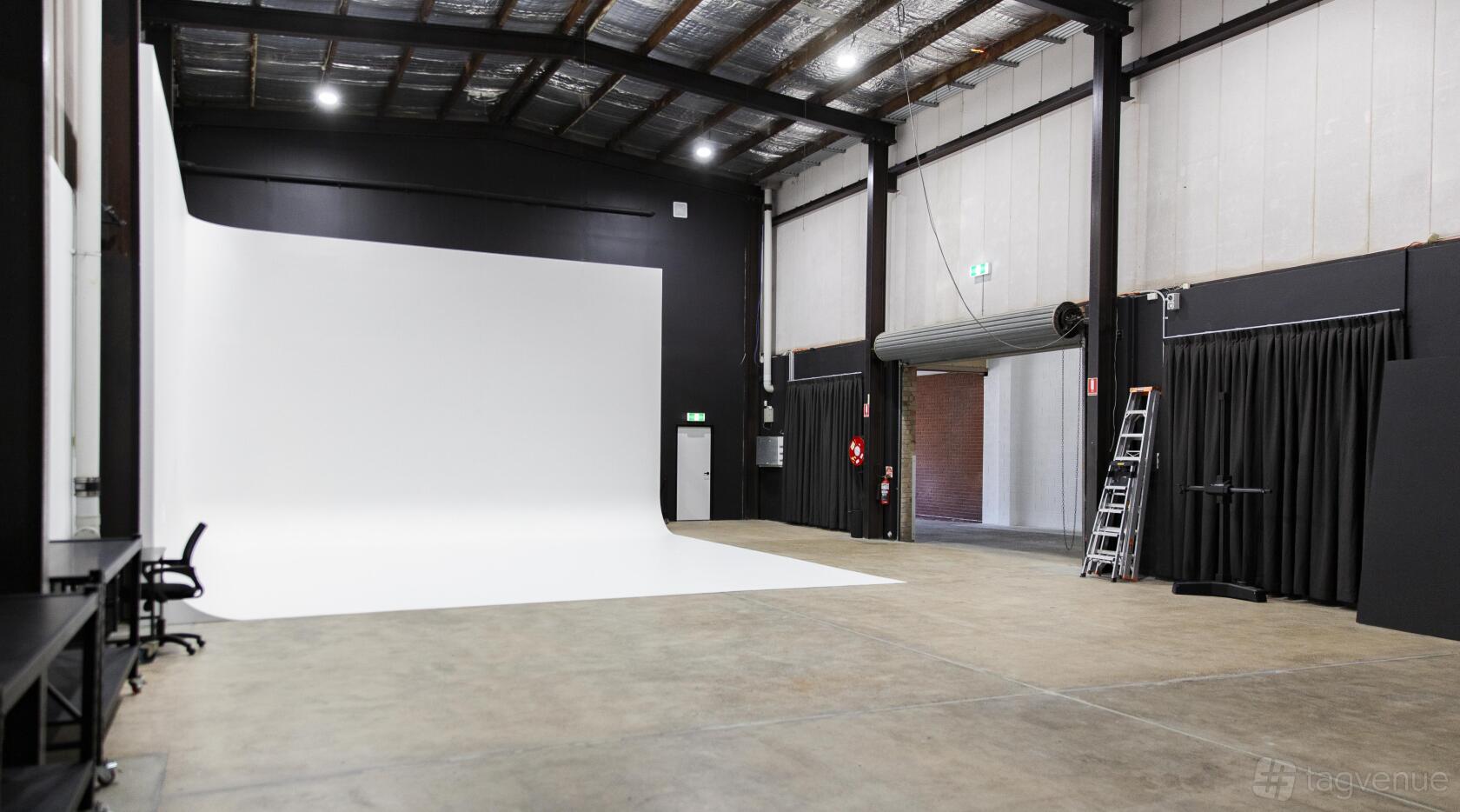 A photo studio with a large white cyclorama, high ceilings, and concrete floors at Studio Salt.