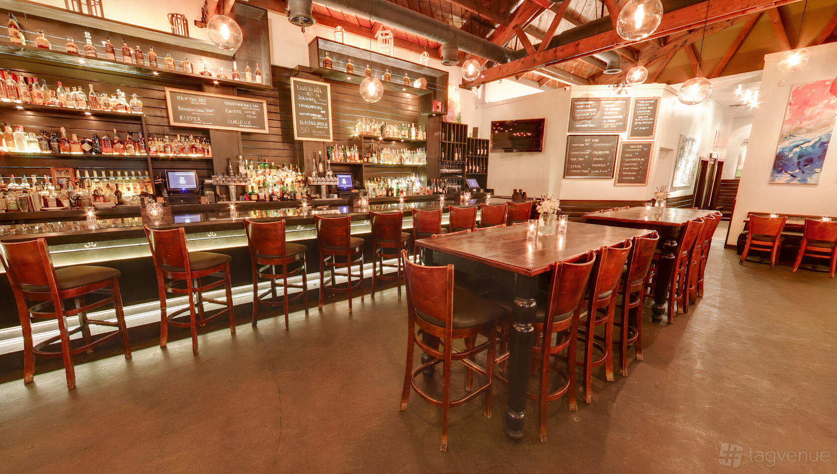 A restaurant with a long polished bar, high-backed wooden chairs, and exposed wooden beams at Upper West.