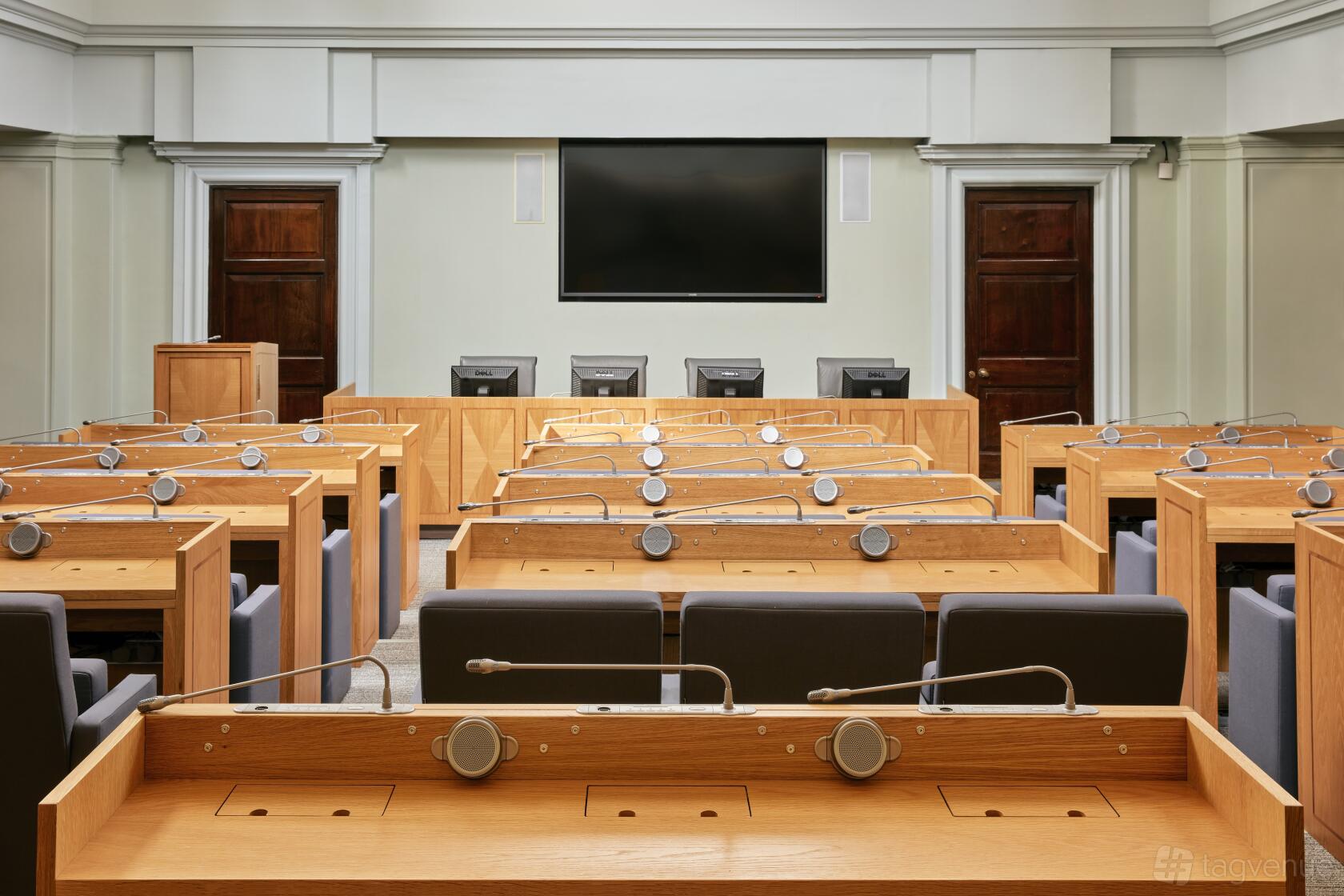 A meeting room with wooden desks, microphones, and a large wall-mounted screen at 113 Chancery Lane.