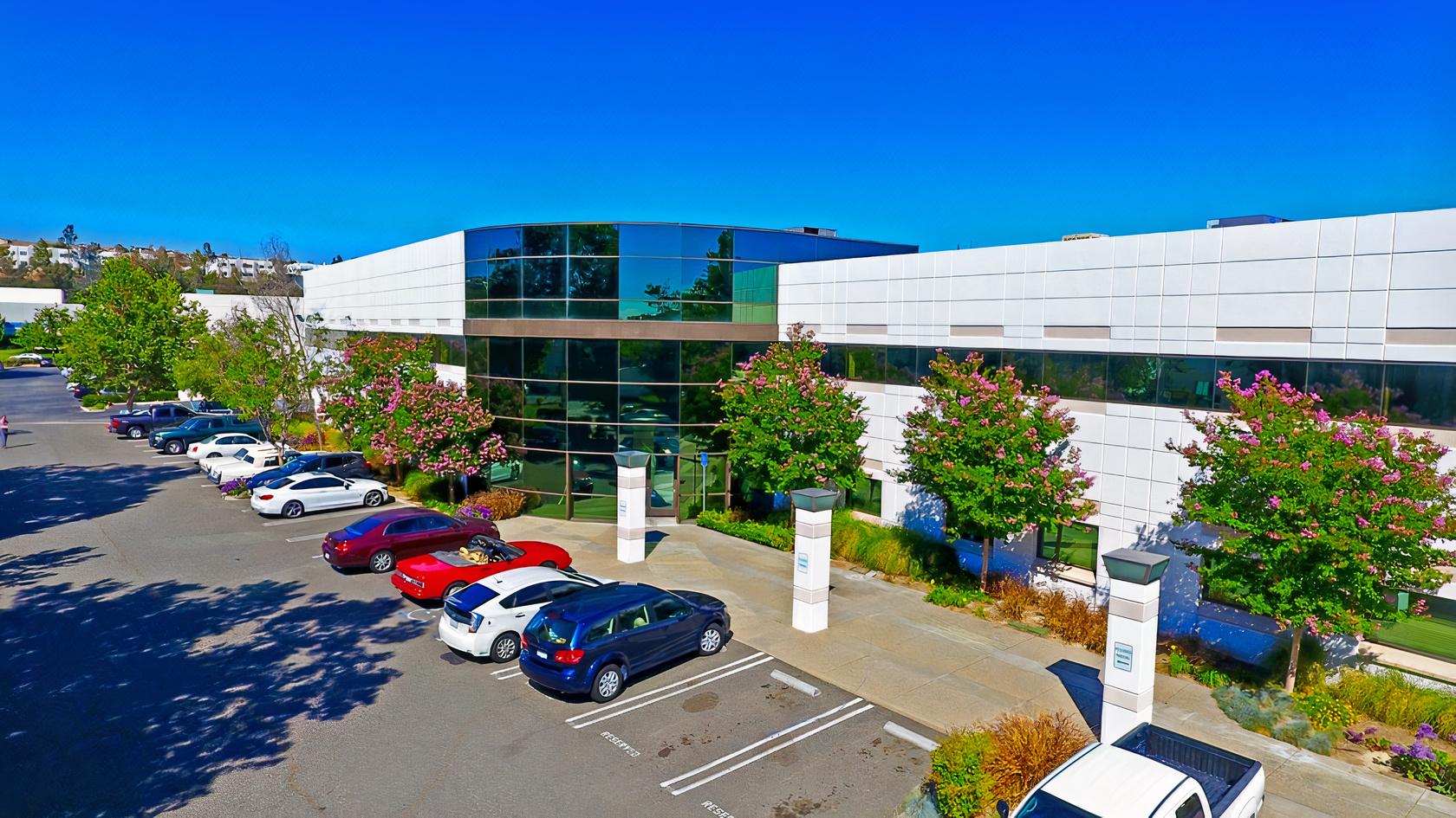 A modern recording studio building with glass windows, white exterior panels, and a parking lot at SCVStudios.