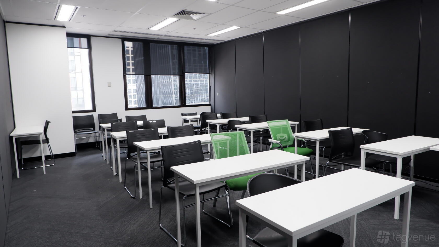 A training room with white rectangular tables, black chairs, and large windows at Melbourne City College Australia.