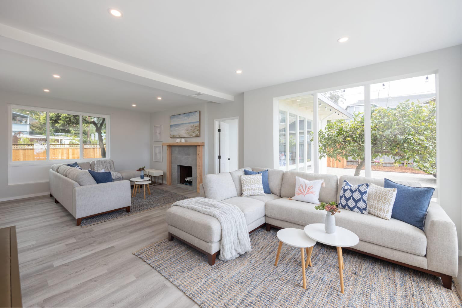 A spacious hotel lounge with large windows, two light gray sectional sofas, and wood flooring at Coastal Estate w/Hot Tub, Ocean Views.