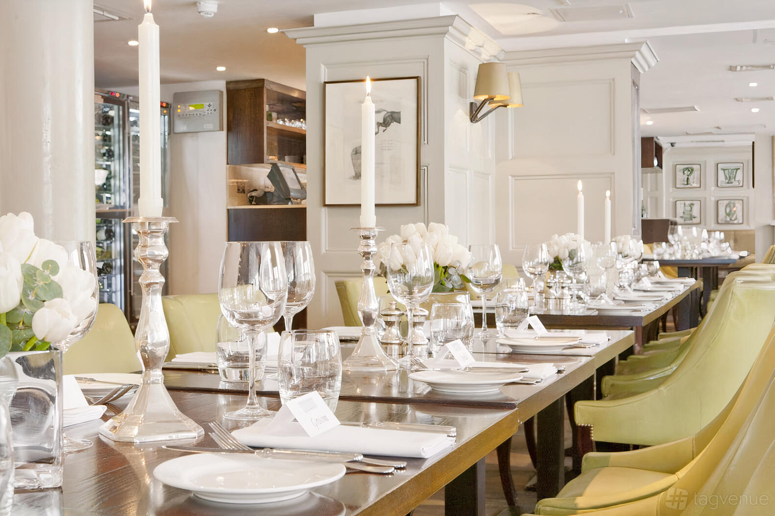 A pub with long banquet tables set with white linens, glassware, and tall candlesticks at Chiswell Street Dining Rooms.