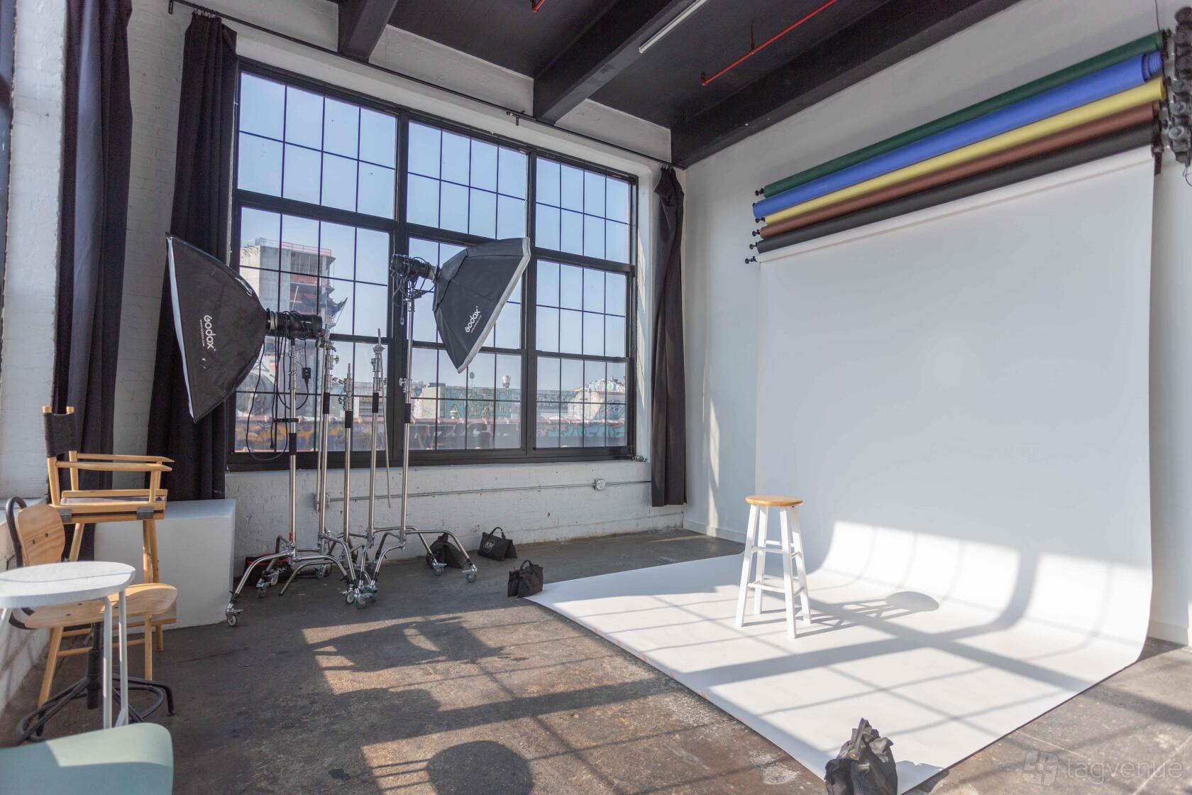 A photo studio with large industrial windows, seamless backdrop, and studio lighting equipment at MikSpace - Stewart Ave.
