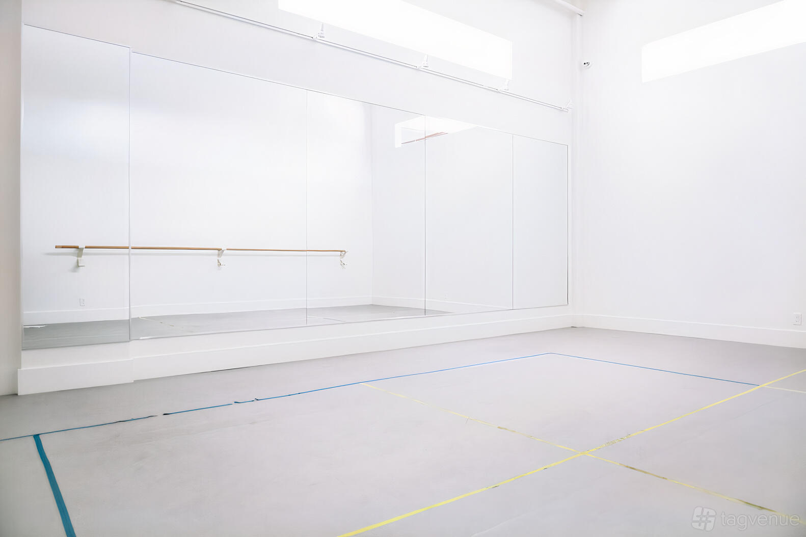 A rehearsal studio with floor-to-ceiling mirrors, a ballet barre, and natural light at City Dance Corps.