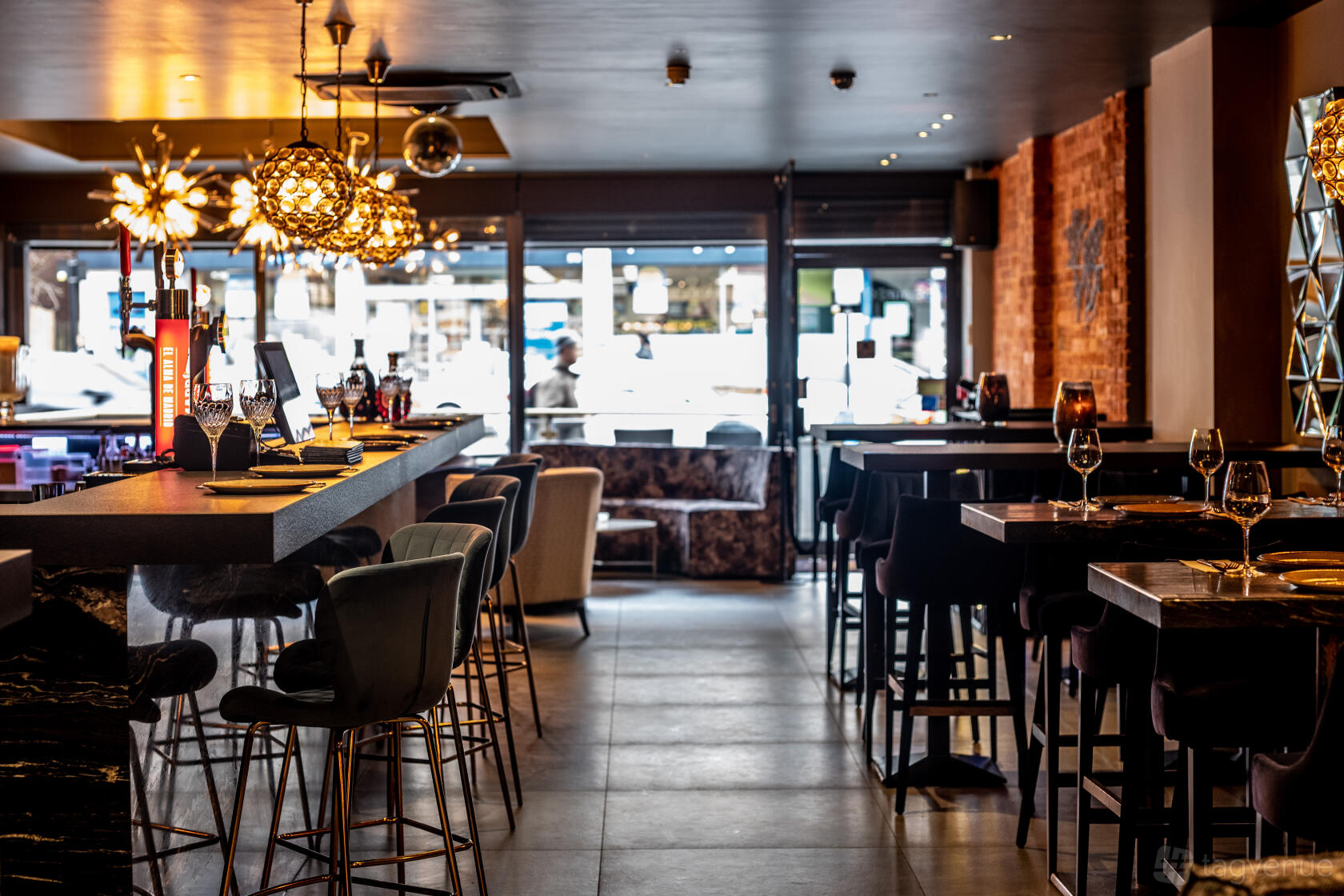 A bar with pendant lighting, high-top tables, plush bar stools, and floor-to-ceiling windows at Fire & Ice Lounge Bar.