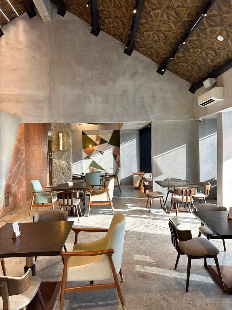 An event space in a cafe with geometric accent wall, wooden tables, and mixed seating at Ms.Durian.