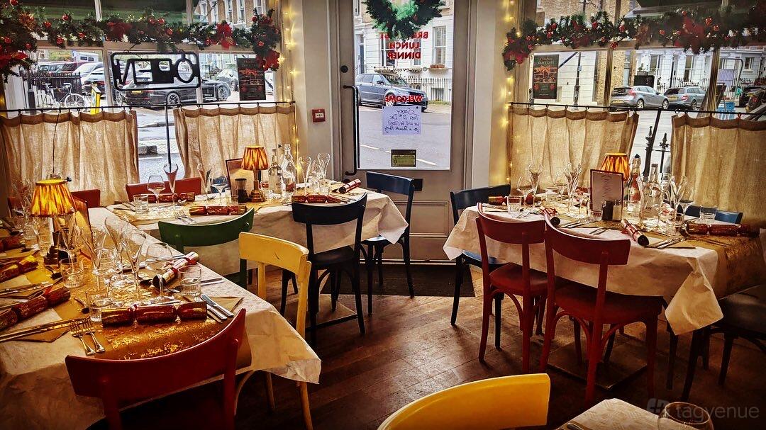 A cafe with colorful chairs, festive garlands, and set tables with glassware at Sams Cafe Primrosehill.