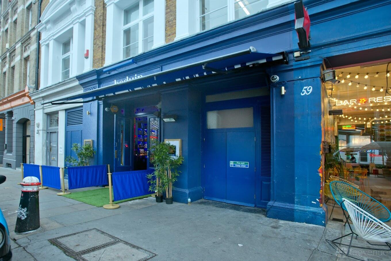 A nightclub entrance with a blue facade, plants by the doorway, and canopy signage at Beduin.