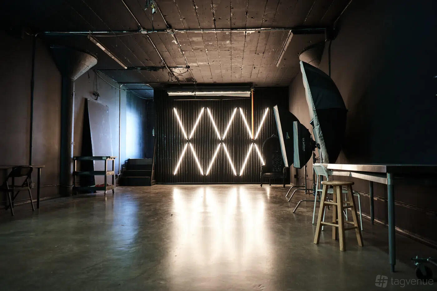 A photo studio with dark walls, geometric LED wall lights, concrete flooring, and photography umbrellas at Main Studios.
