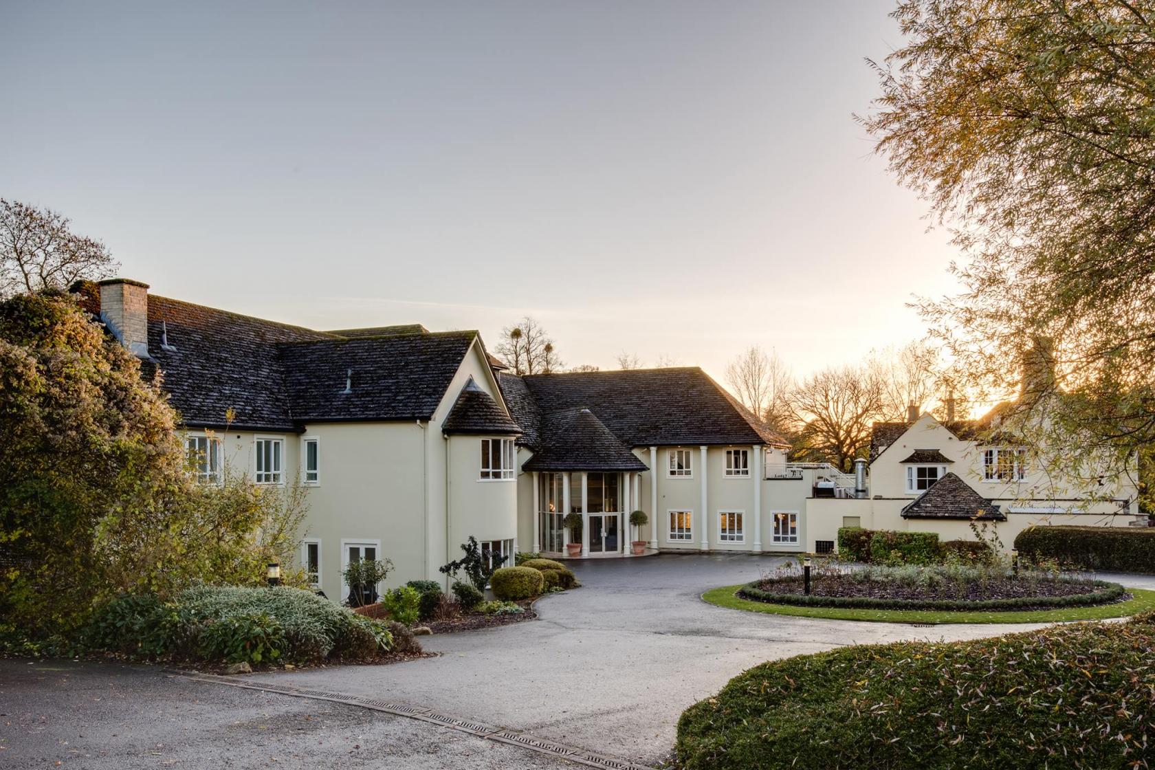 A hotel with a cream exterior, pitched roofs, and landscaped gardens at Sudbury House Hotel.
