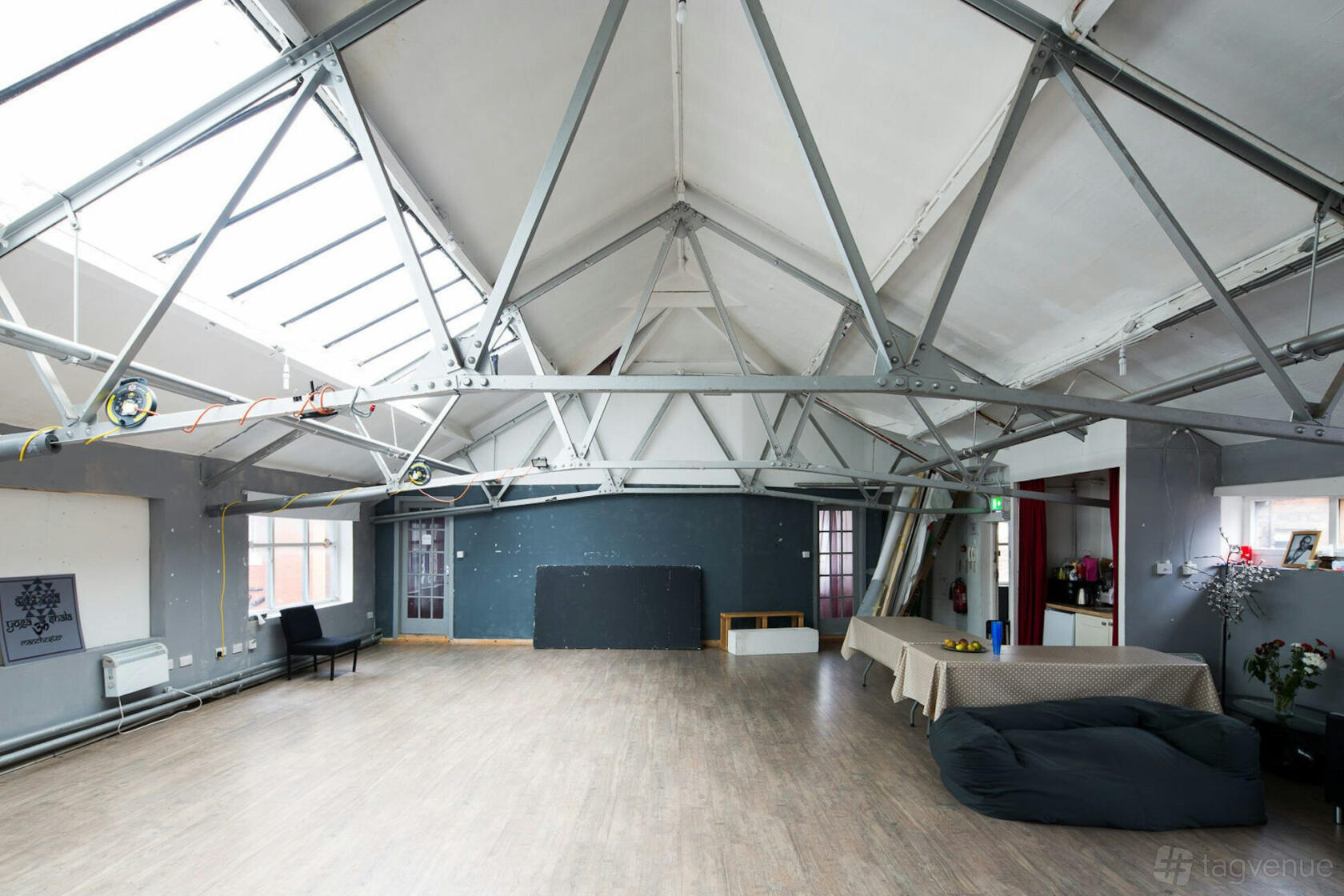A photo studio with skylights, exposed steel beams, and wood flooring at Studio Bee Photography Studio.