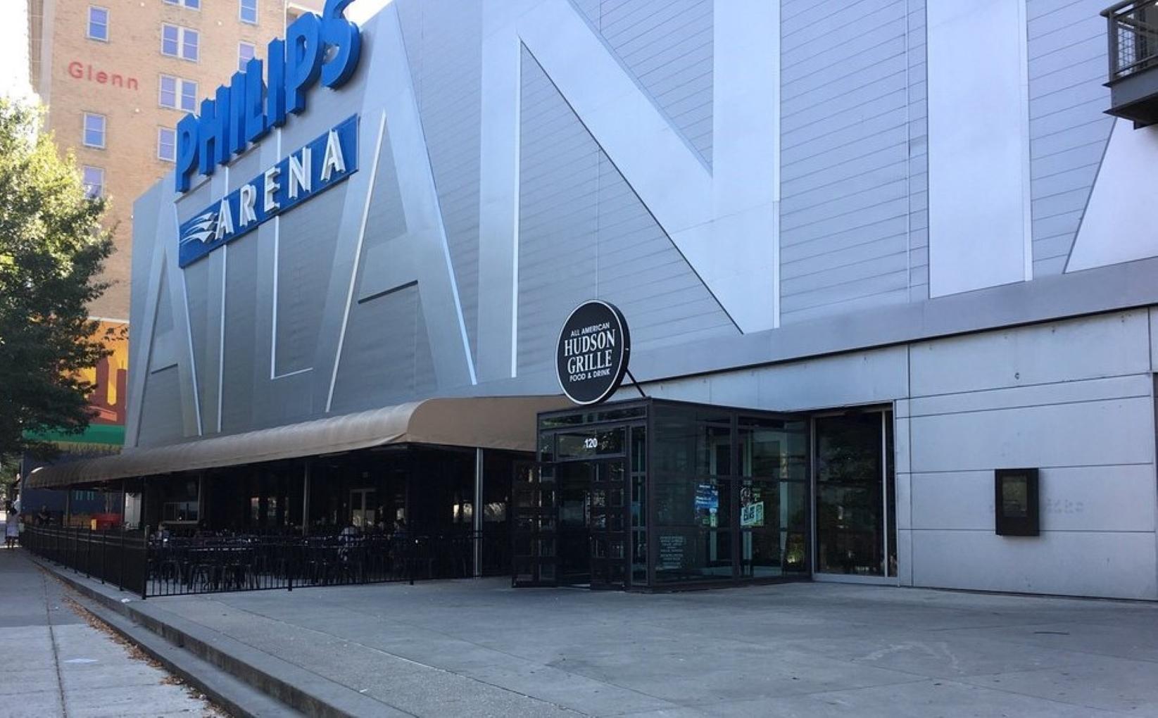A pub with a glass entrance, outdoor seating, and metal signage at Hudson Grille - Downtown.
