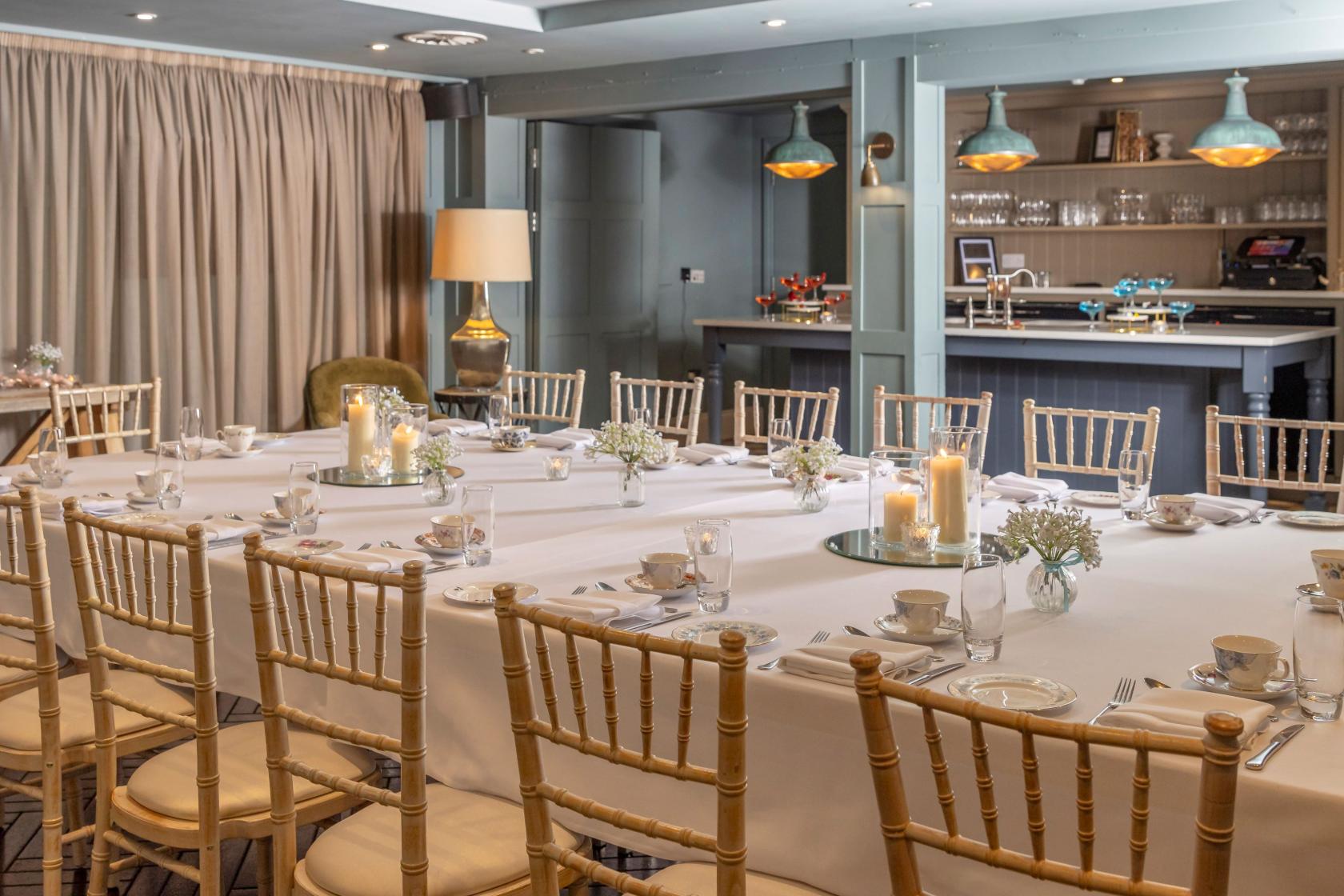 A function room with white table linens, wooden chairs, and candle centerpieces at King Street Townhouse.