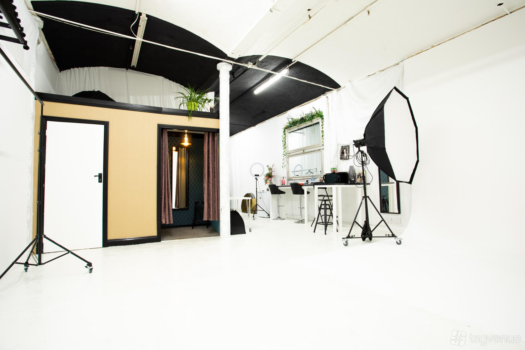 A photo studio with white floors, a curved cyclorama wall, black ceiling, and lighting equipment at The Photocove.