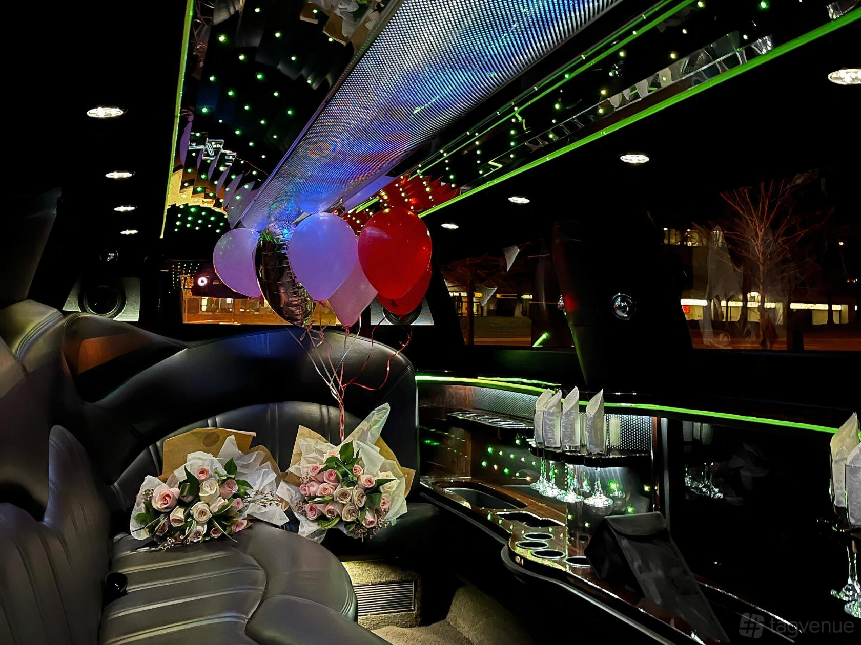A party bus with leather seating, colorful LED ceiling lights, balloons, and floral bouquets at Platinum Rides.