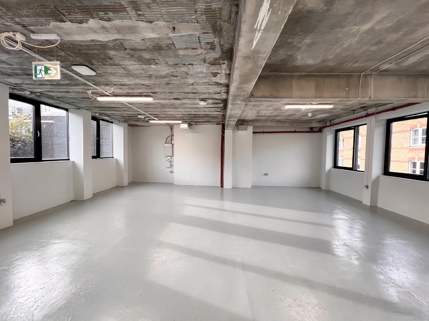 A function room with exposed concrete ceilings, large windows, and white walls at The Africa Centre.