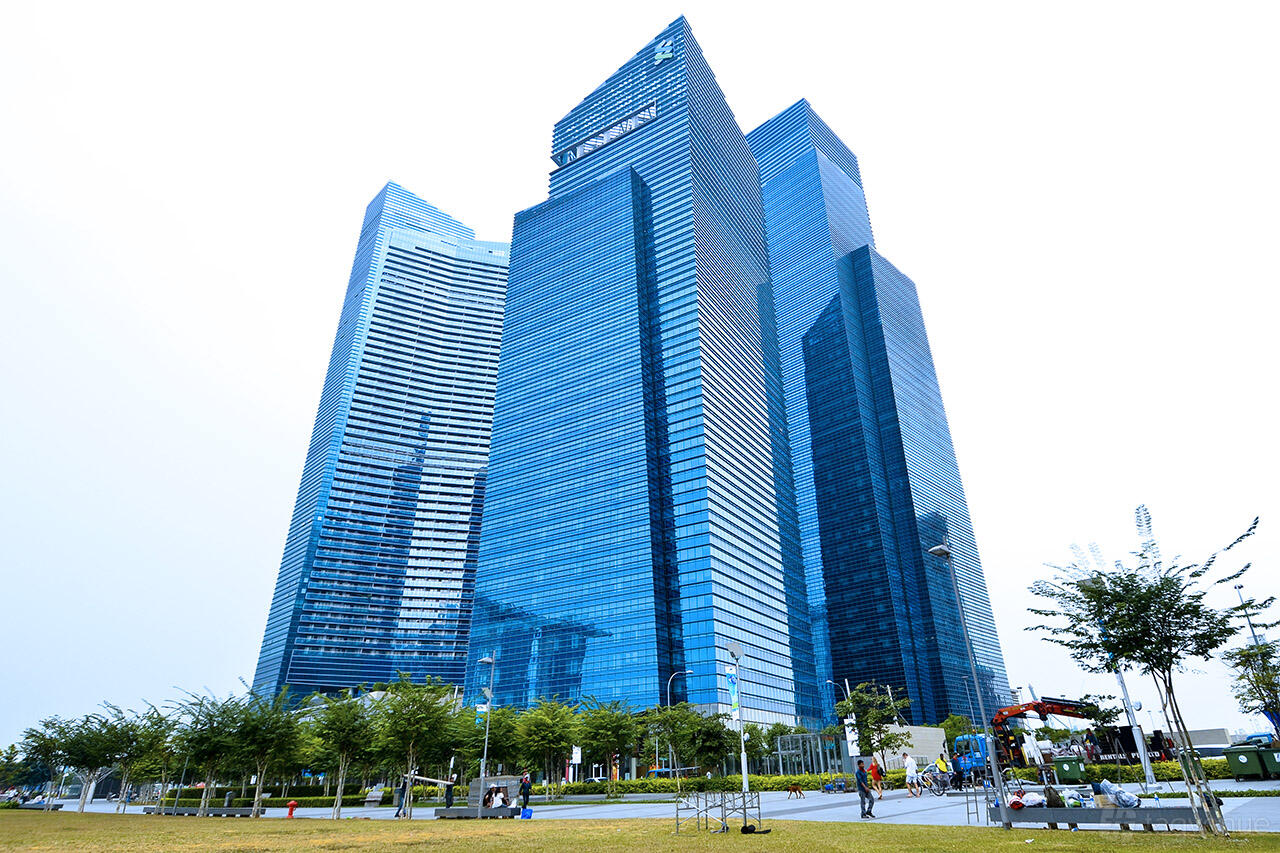 A meeting centre with blue glass skyscrapers and landscaped green space at Marina Bay Financial Centre Tower 1.