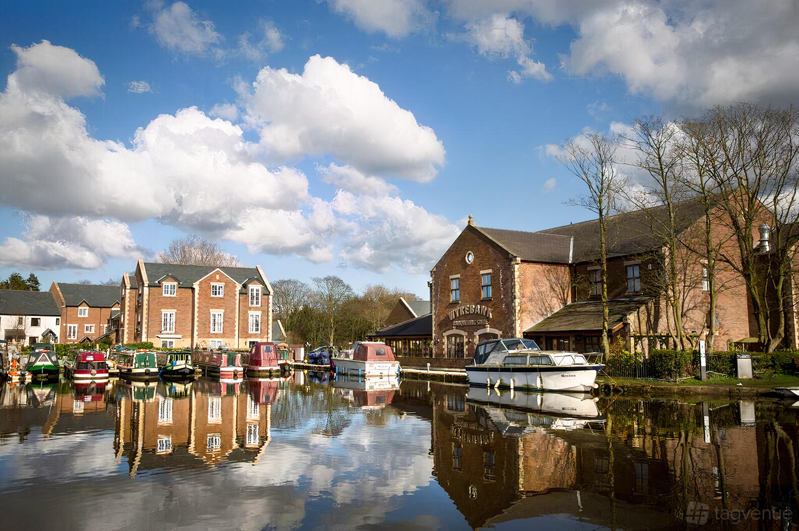 A historic building with red brick exterior and canal-side moorings for boats at Wyrebank.