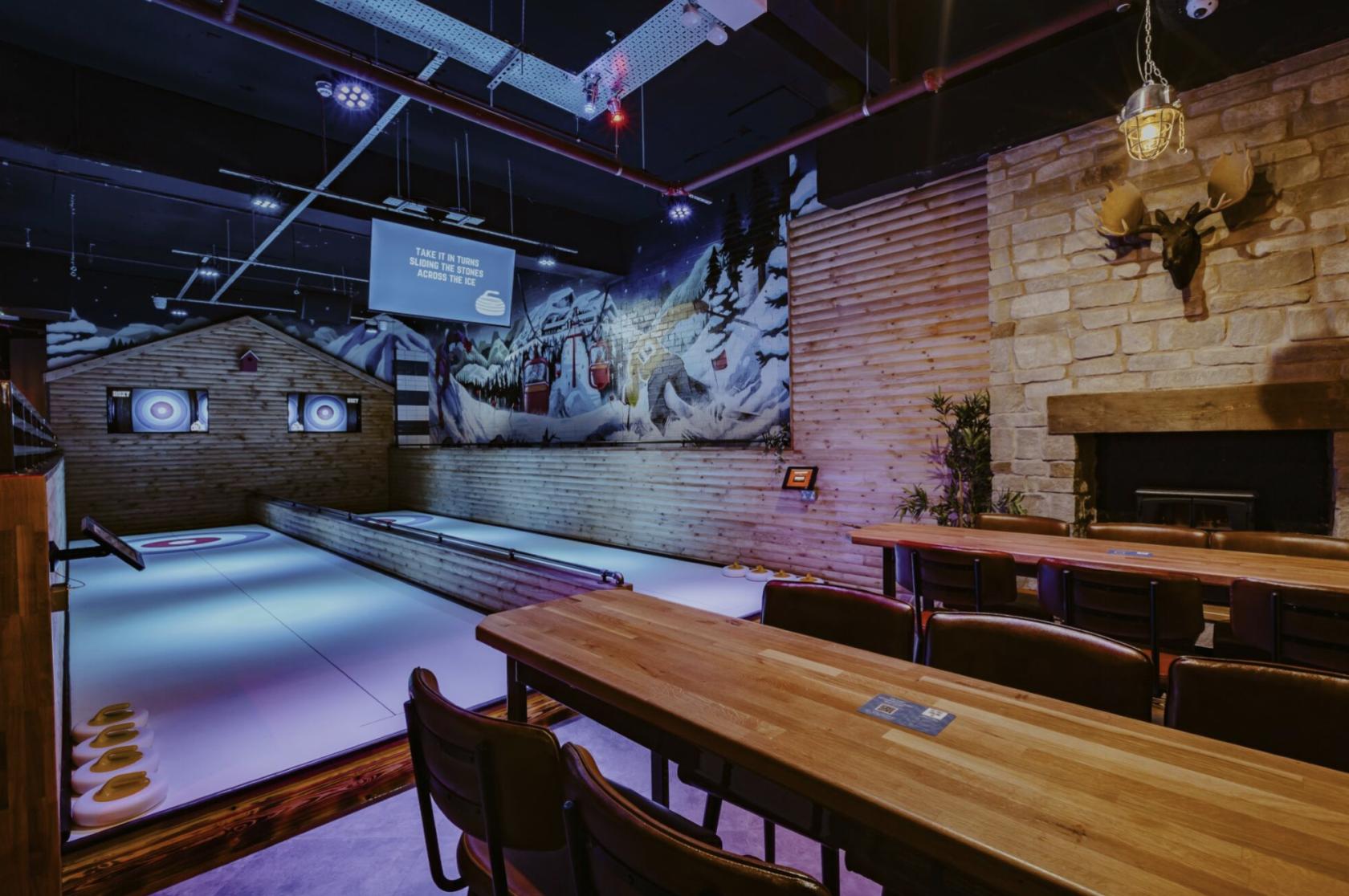 An event space in a bar with wooden tables, curling lanes, and mural walls at Roxy Lanes Liverpool School Lane.
