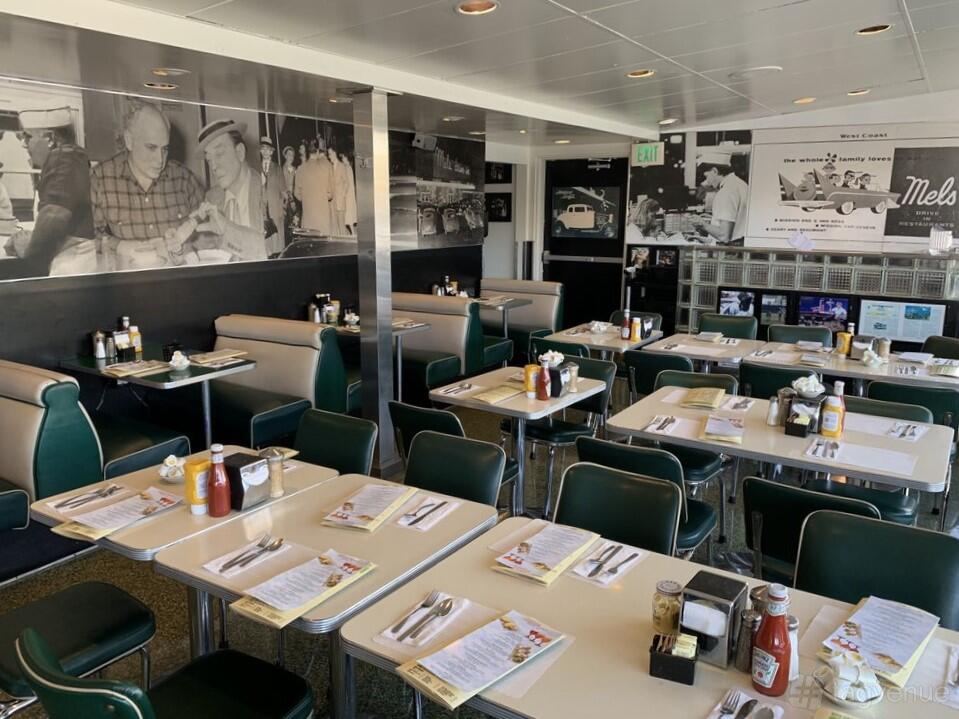 A restaurant with retro diner booths, black and white wall murals, and vintage decor at Mel's Drive-In Geary Boulevard.