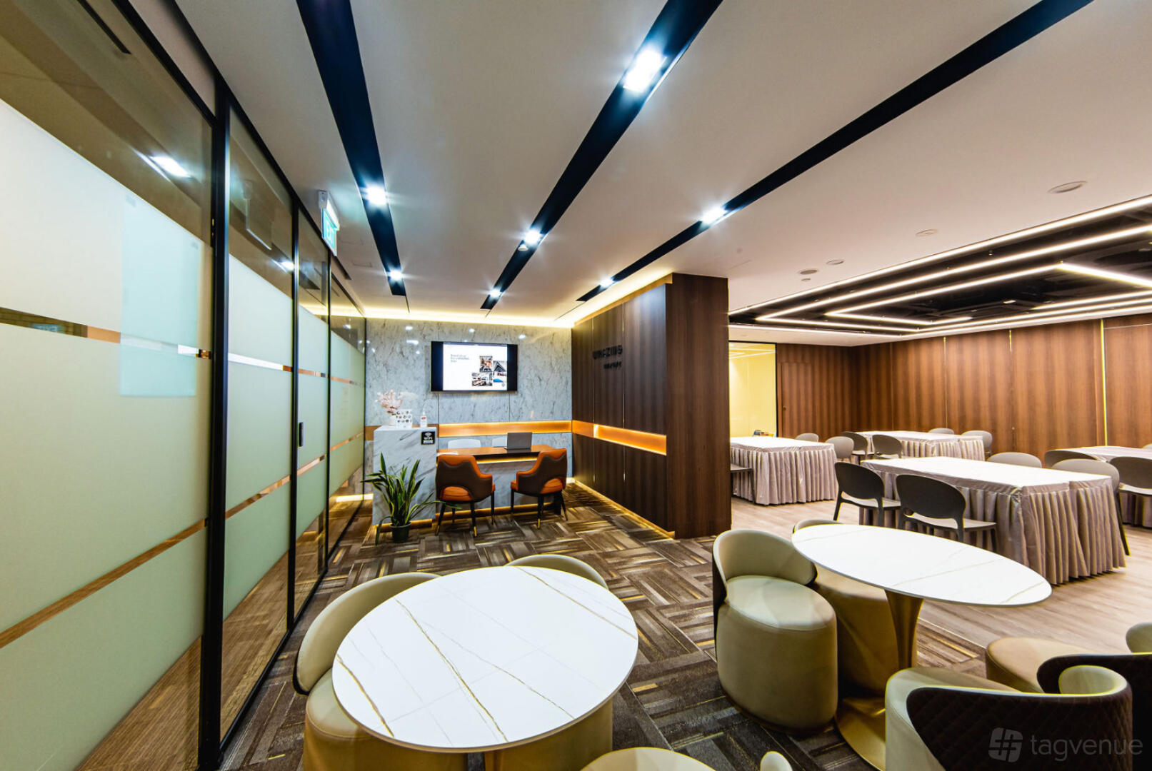 A meeting room with round white tables, padded chairs, and wood panel accents at Umazing Events.