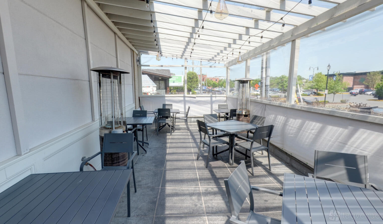An outdoor event space with a covered patio, string lights, and metal tables at Telly's Taverna.