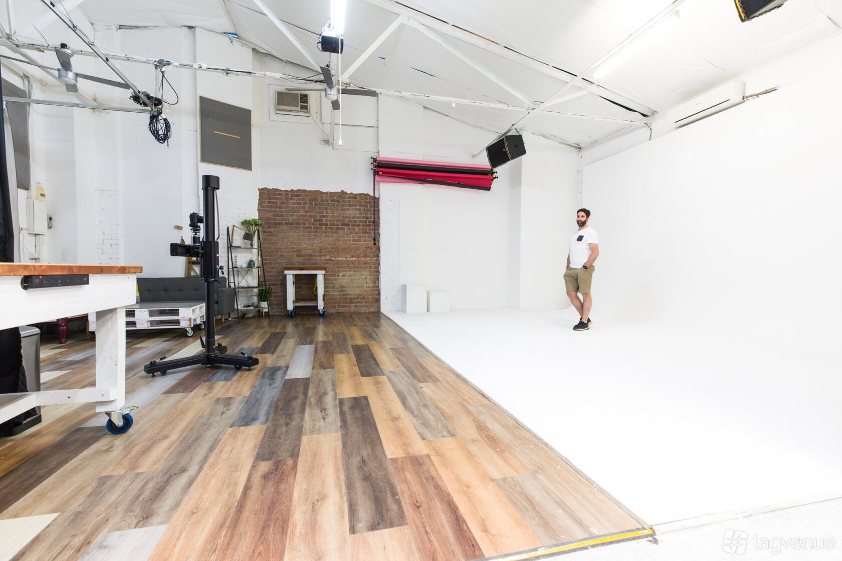 A photo studio with a spacious white cyclorama wall, wood flooring, and exposed brick accents at Epic Studios.