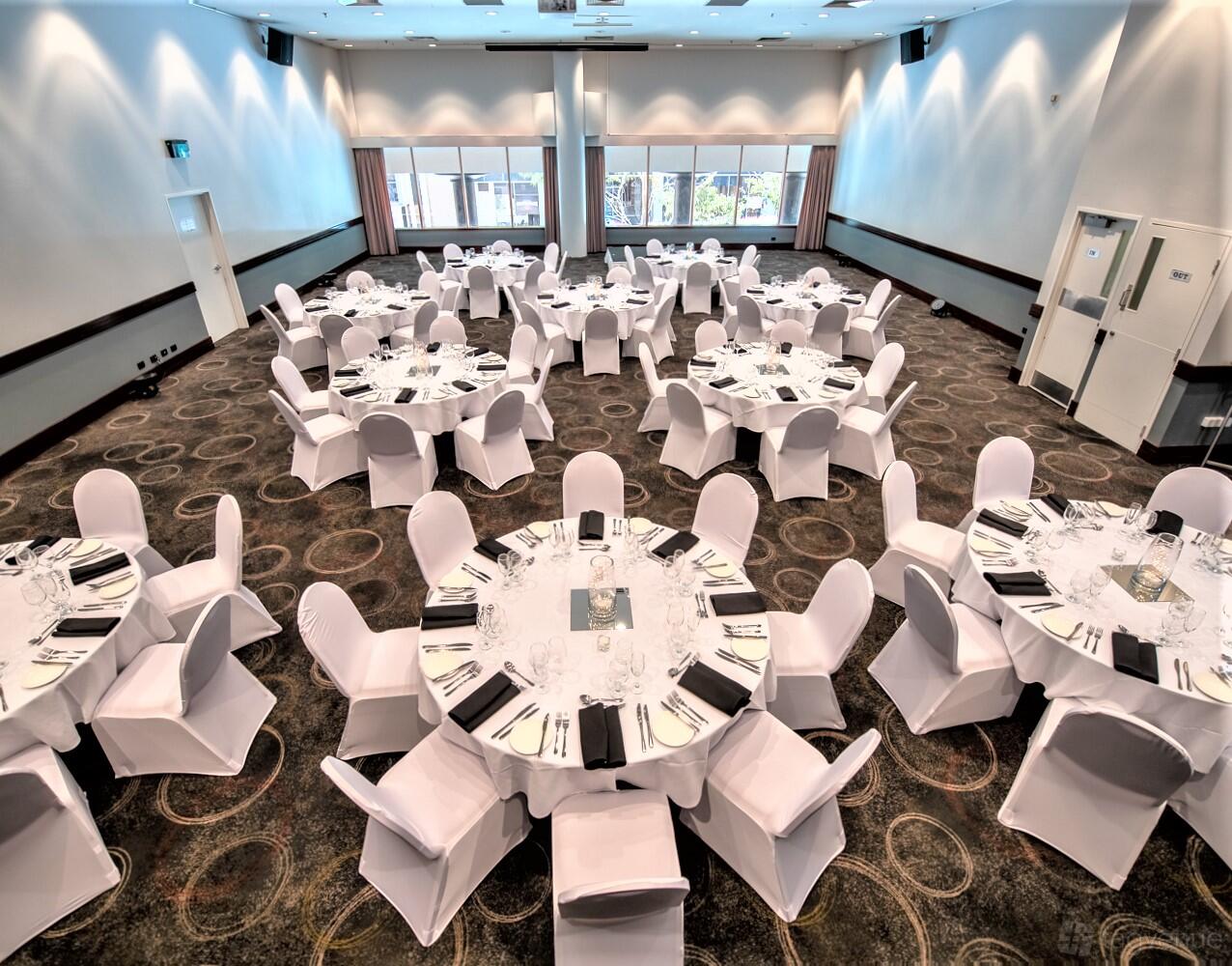 A function room with round tables covered in white linens and large windows at Novotel Perth Langley.