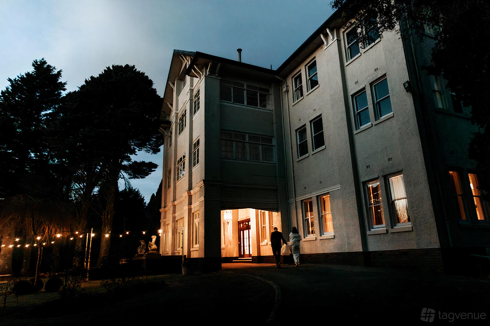 A historic hotel exterior with warm lighting, large windows, and string lights at The Robertson Hotel.