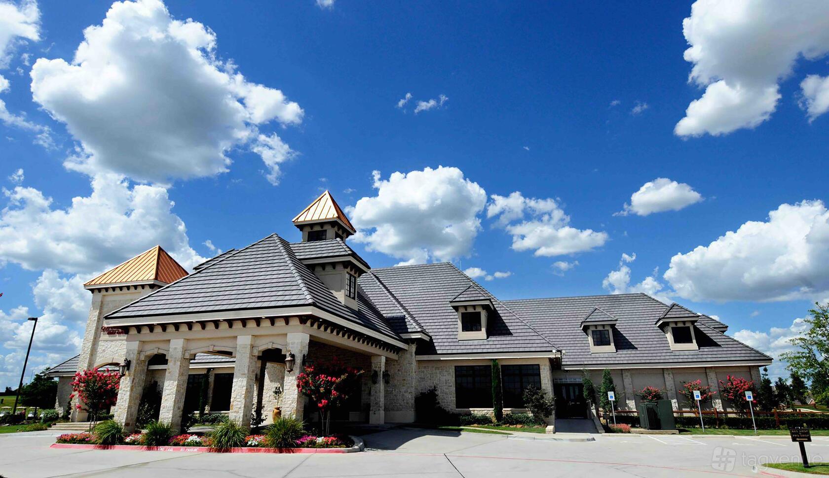 A golf club with stone exterior walls, gabled roofs, and landscaped entry at Coyote Ridge Golf Club.