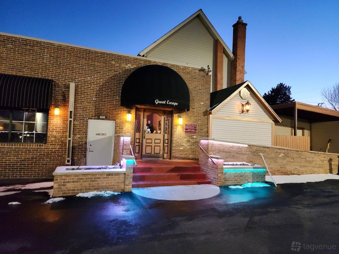 A restaurant with brick exterior, arched black awning, and warmly lit entrance at Great Escape Restaurant.