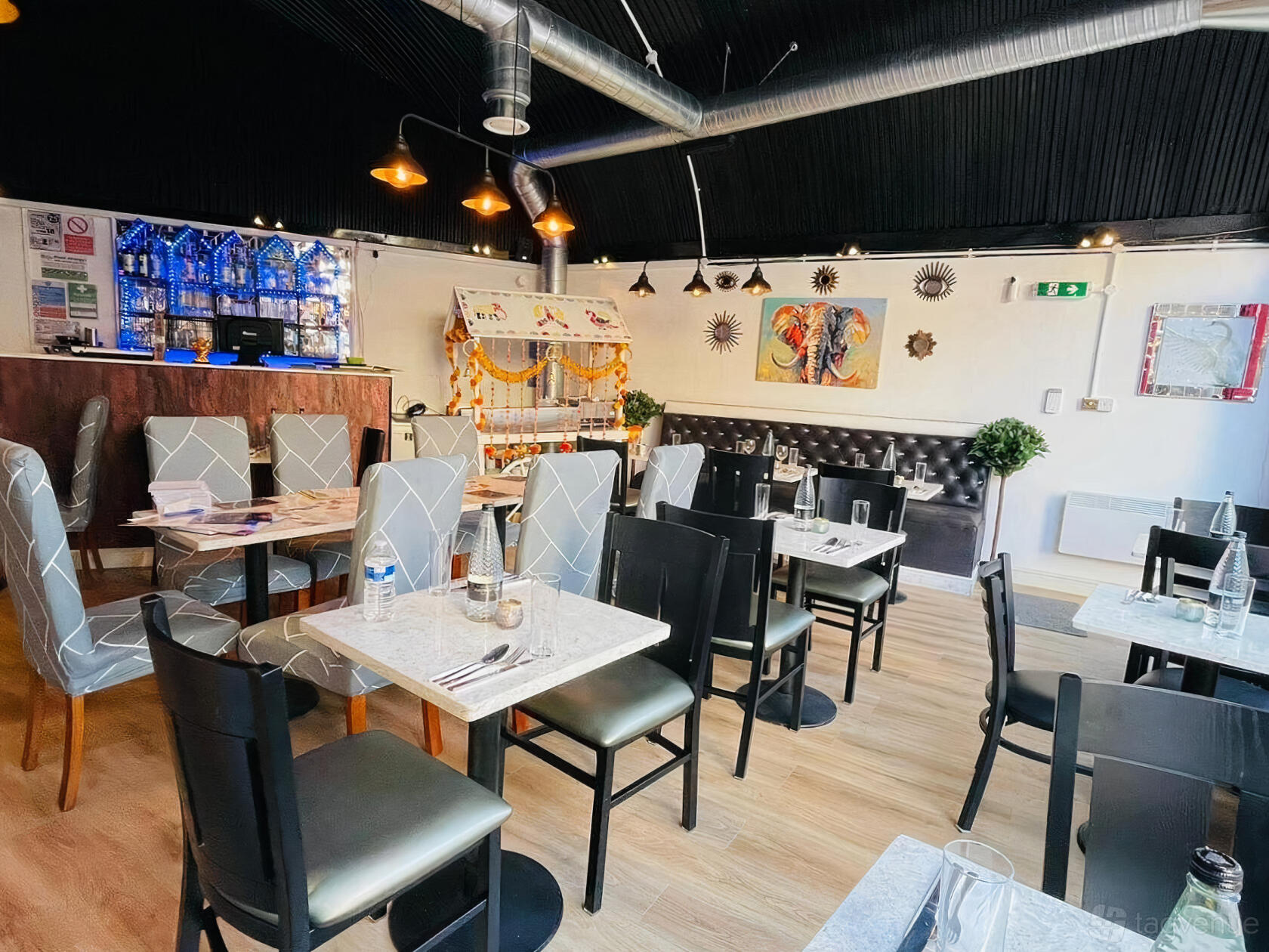 An event space in a restaurant with marble-topped tables, mixed seating, and wall art at Delhi wala Food.